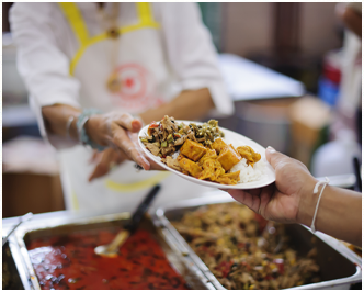 A person handing a plate of food to another person